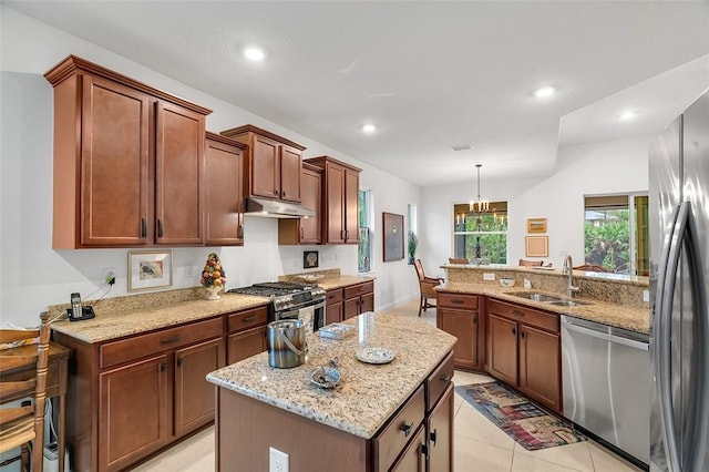 kitchen featuring a kitchen island, pendant lighting, sink, light stone counters, and stainless steel appliances