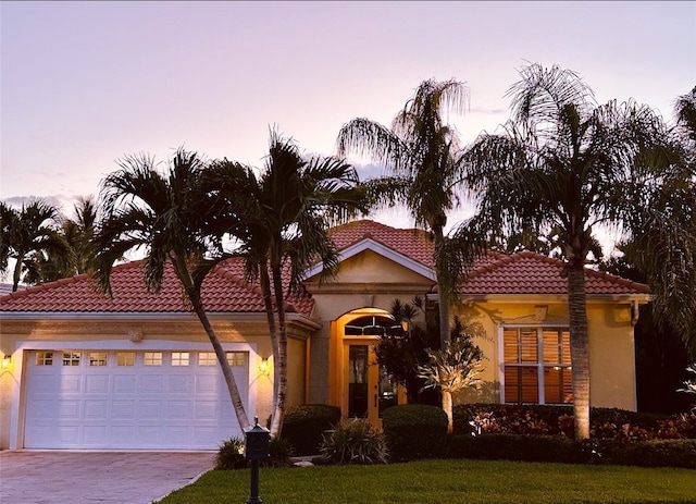 mediterranean / spanish-style house featuring a garage and a lawn