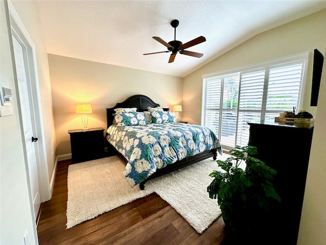 bedroom with ceiling fan, dark wood-type flooring, and vaulted ceiling