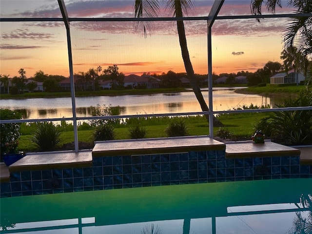 pool at dusk featuring glass enclosure and a water view