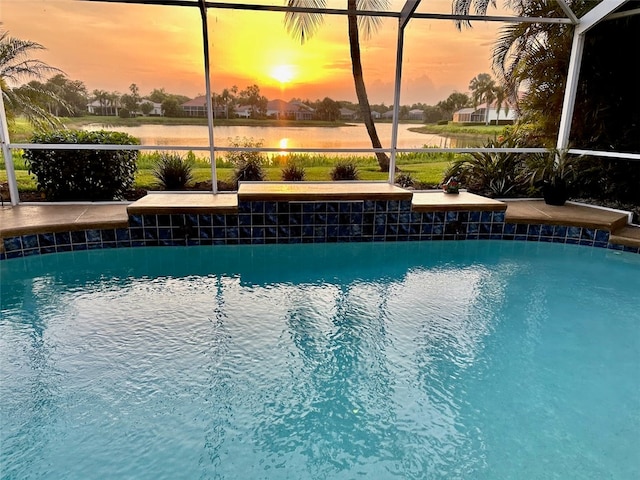 pool at dusk featuring a water view and glass enclosure