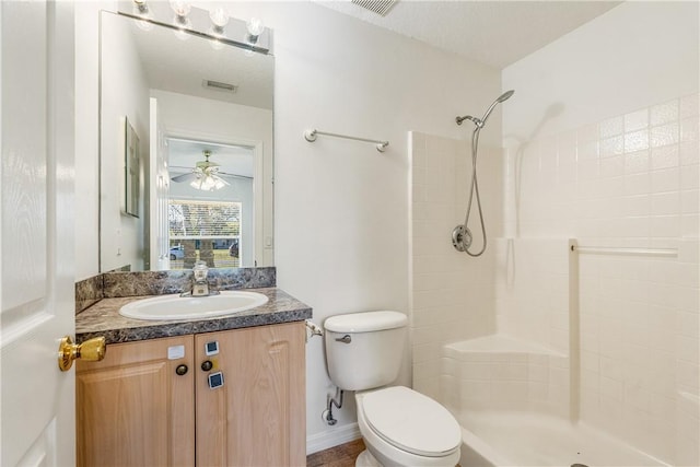 bathroom with a textured ceiling, vanity, ceiling fan, a shower, and toilet