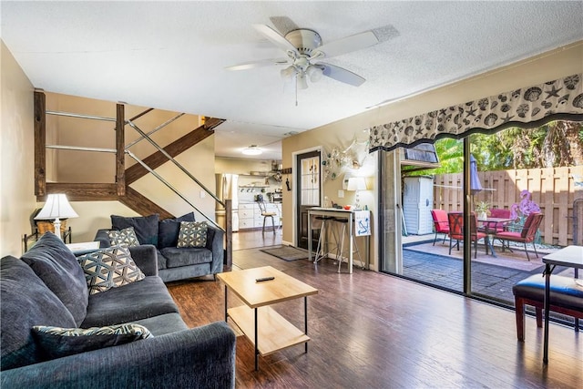 living room featuring ceiling fan, dark wood-type flooring, and a textured ceiling