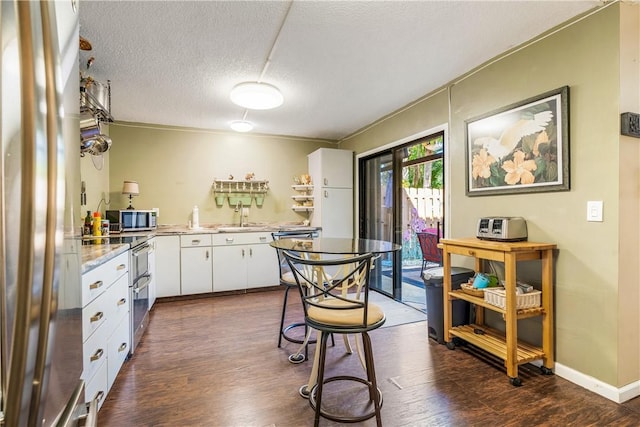 kitchen with sink, white cabinetry, a textured ceiling, ornamental molding, and stainless steel appliances