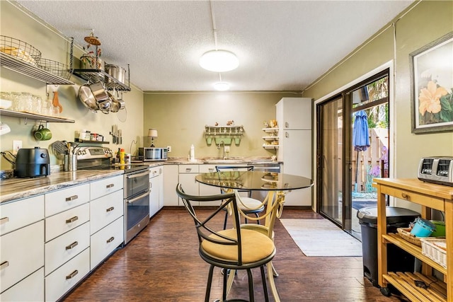 kitchen featuring a textured ceiling, dark hardwood / wood-style floors, white cabinetry, and stainless steel appliances