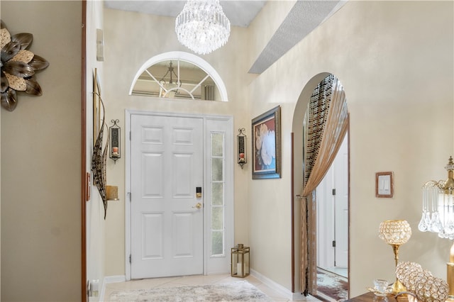 foyer featuring light tile patterned floors, a high ceiling, and an inviting chandelier