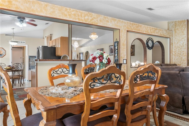 tiled dining area with vaulted ceiling, ceiling fan, and a textured ceiling