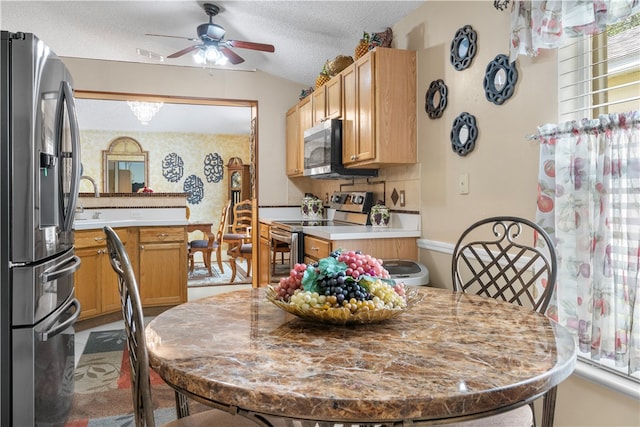 dining space featuring a textured ceiling, ceiling fan, and vaulted ceiling