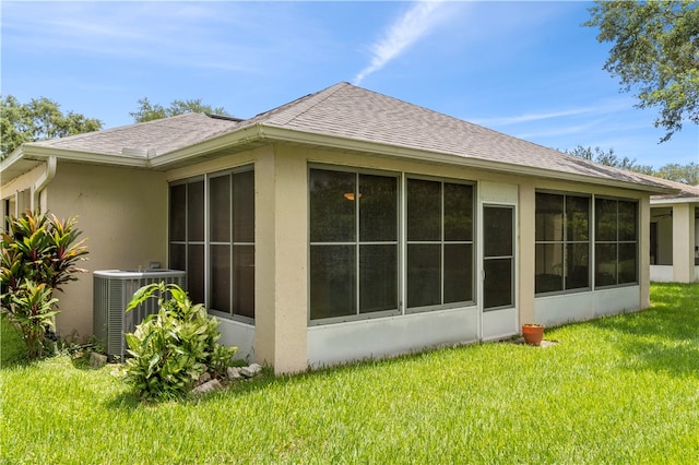 view of side of home with central AC unit, a sunroom, and a yard