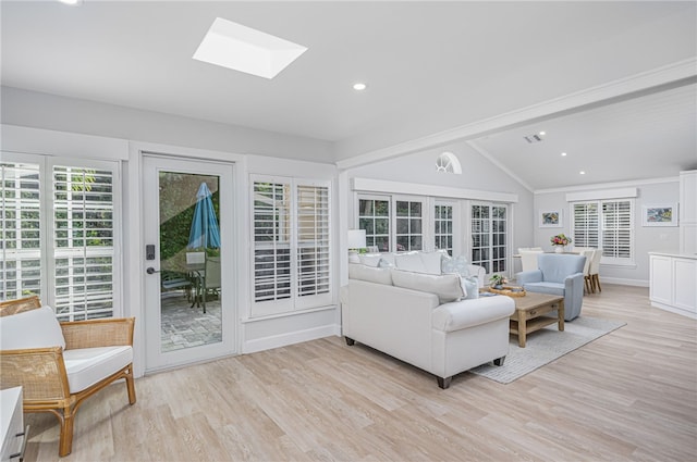 living room featuring vaulted ceiling with skylight and light hardwood / wood-style floors