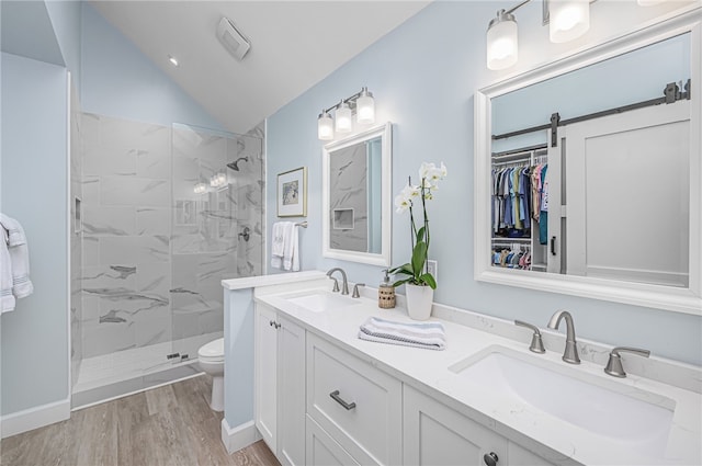 bathroom with wood-type flooring, vaulted ceiling, toilet, tiled shower, and vanity