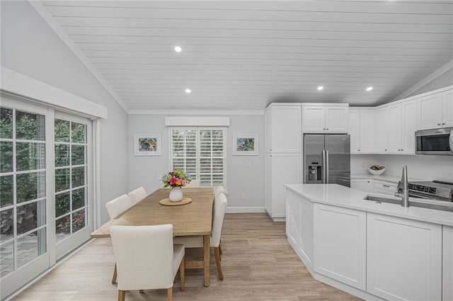 kitchen with white cabinets, a wealth of natural light, appliances with stainless steel finishes, and vaulted ceiling