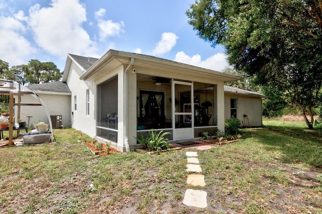 rear view of property featuring central AC unit, ceiling fan, a yard, and a sunroom