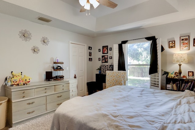 carpeted bedroom featuring a tray ceiling and ceiling fan