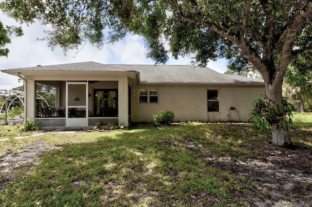 back of property featuring a sunroom and a lawn