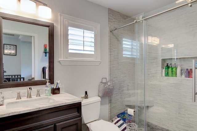 bathroom with a shower with door, vanity, and toilet