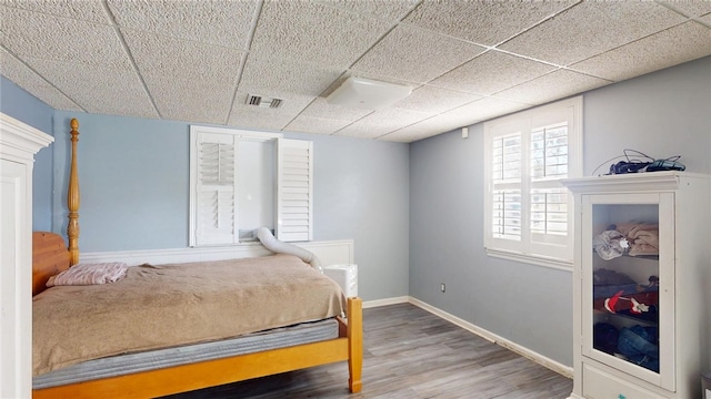 bedroom with wood-type flooring and a drop ceiling