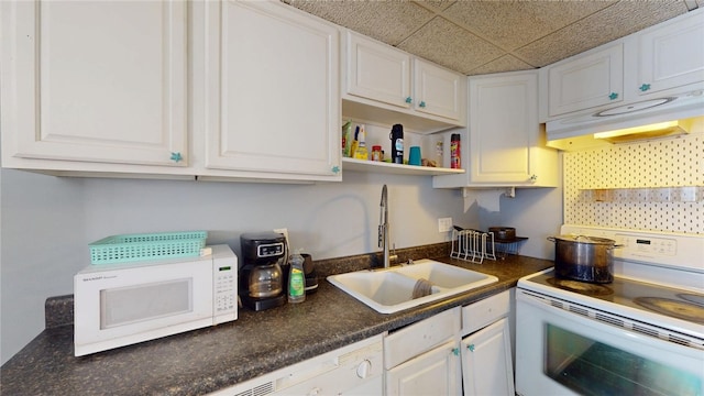 kitchen featuring white appliances, a drop ceiling, sink, and white cabinets