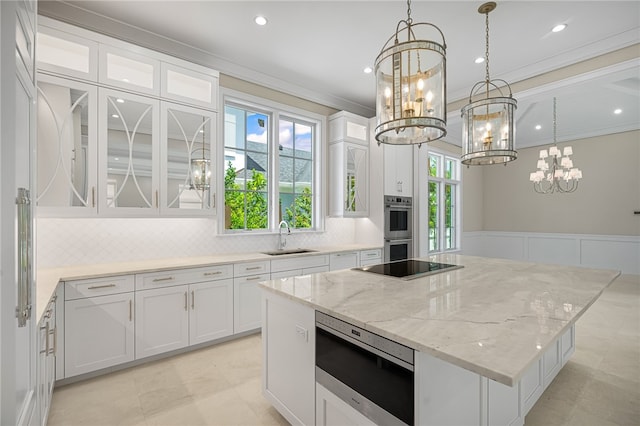 kitchen with appliances with stainless steel finishes, white cabinetry, sink, and a kitchen island