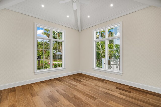 unfurnished room featuring ceiling fan, light wood-type flooring, and lofted ceiling with beams