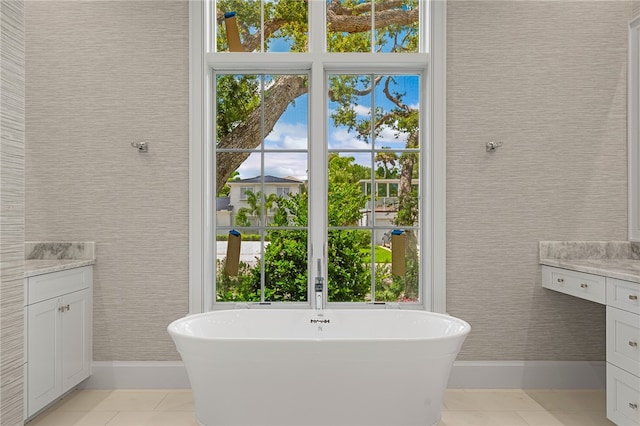 bathroom with a washtub, vanity, and tile patterned flooring