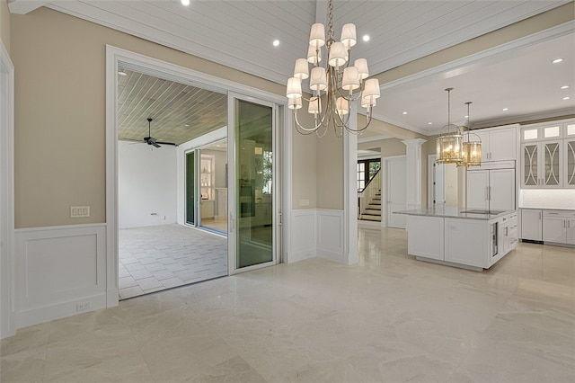 unfurnished dining area featuring ornamental molding, decorative columns, and ceiling fan