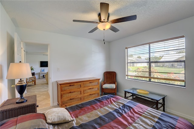 bedroom with ceiling fan and a textured ceiling