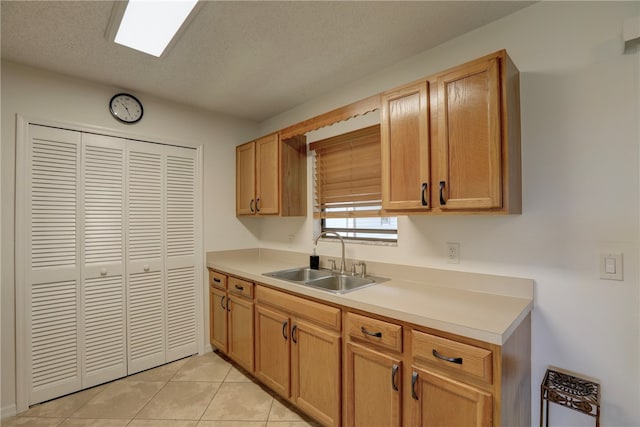 kitchen featuring a textured ceiling, sink, and light tile patterned flooring