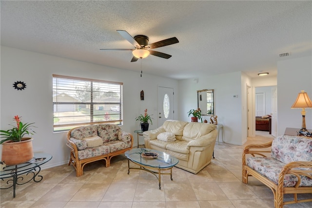 living room with a textured ceiling, ceiling fan, and light tile patterned floors