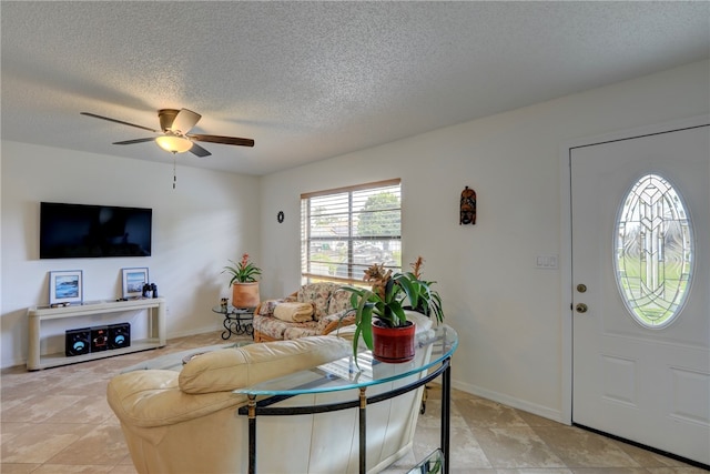 interior space with a textured ceiling, ceiling fan, and light tile patterned flooring