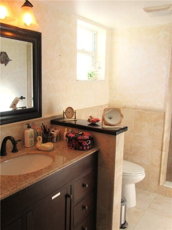 bathroom featuring tile patterned flooring, vanity, toilet, and tile walls