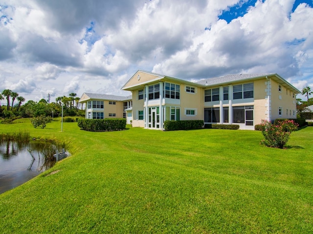 rear view of property with a water view and a yard