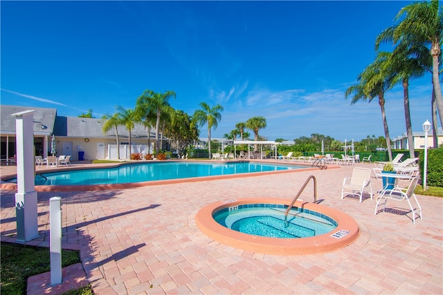 view of swimming pool featuring a hot tub and a patio area