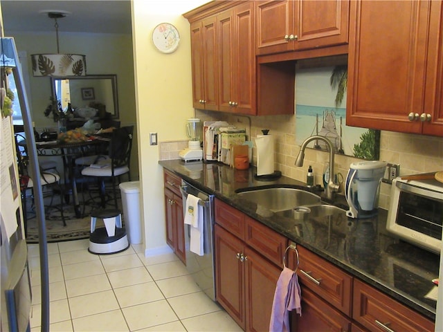 kitchen with tasteful backsplash, stainless steel dishwasher, sink, dark stone countertops, and light tile patterned flooring