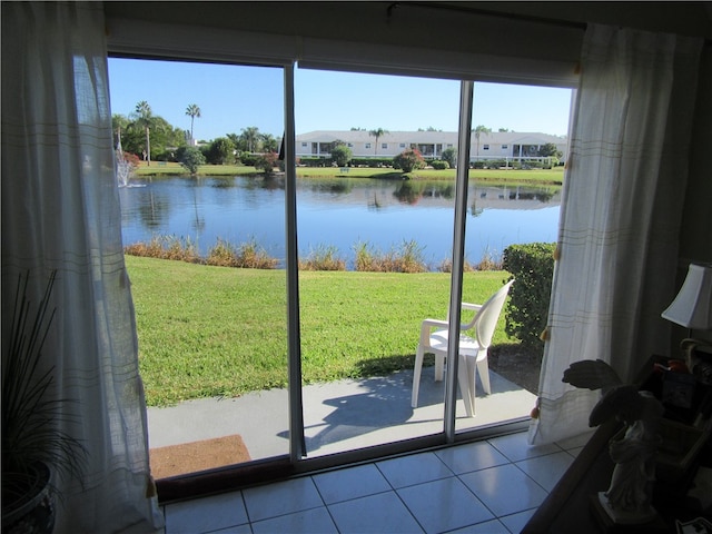 doorway to outside with a water view, a healthy amount of sunlight, and light tile patterned floors