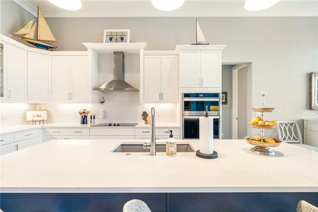 9266 Orchid Cove Cir, Vero Beach, FL 32963 - kitchen with wall chimney exhaust hood, double oven, white cabinetry, and light countertops