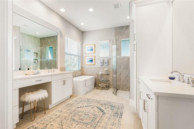 9266 Orchid Cove Cir, Vero Beach, FL 32963 - bathroom featuring a tile shower, two vanities, a garden tub, and recessed lighting