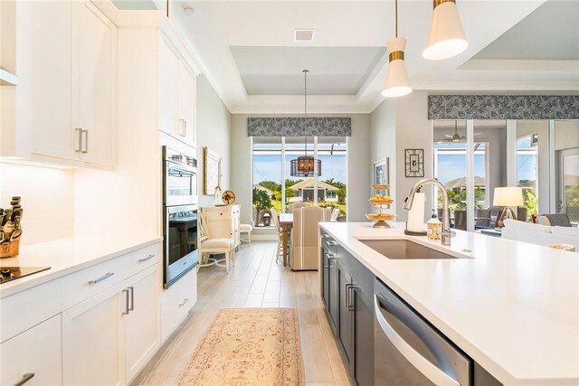 9266 Orchid Cove Cir, Vero Beach, FL 32963 - kitchen with stainless steel appliances, a tray ceiling, white cabinetry, light wood-type flooring, and light countertops