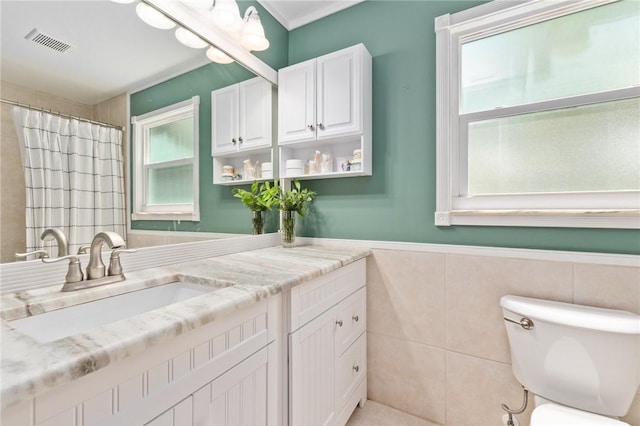 bathroom featuring toilet, tile walls, and vanity