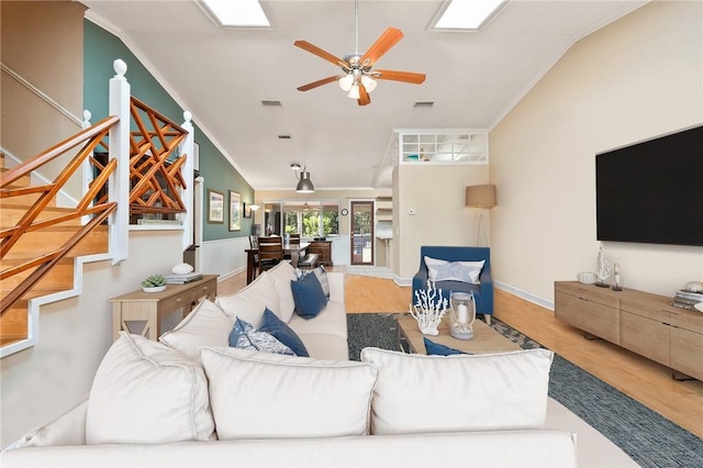 living room featuring ceiling fan, lofted ceiling with skylight, ornamental molding, and hardwood / wood-style floors