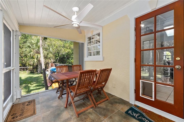 sunroom / solarium with lofted ceiling, ceiling fan, wood ceiling, and a wealth of natural light