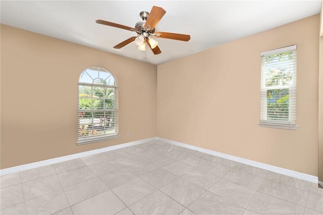 tiled empty room with ceiling fan and a wealth of natural light