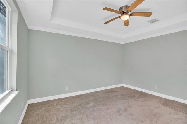 carpeted empty room featuring a tray ceiling, ceiling fan, and crown molding