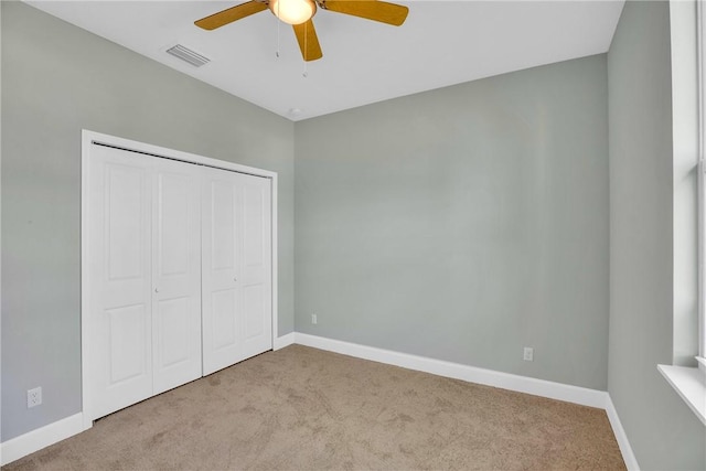 unfurnished bedroom with ceiling fan, a closet, and light carpet