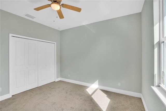 unfurnished bedroom with ceiling fan, a closet, and light colored carpet