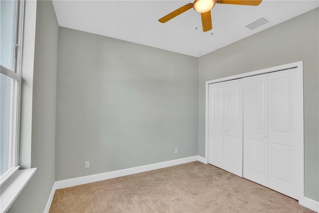 unfurnished bedroom featuring ceiling fan, a closet, and light carpet