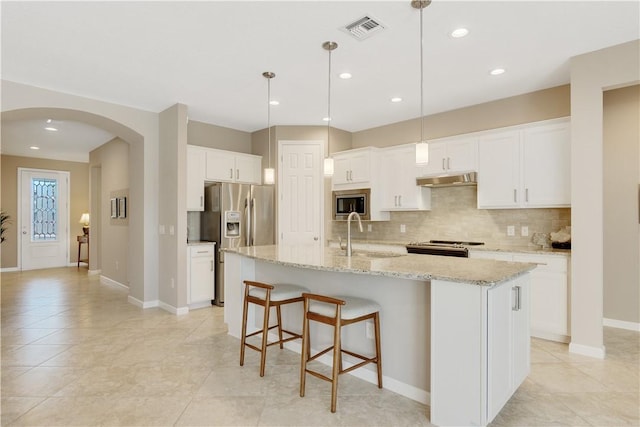 kitchen featuring hanging light fixtures, a center island with sink, and white cabinets