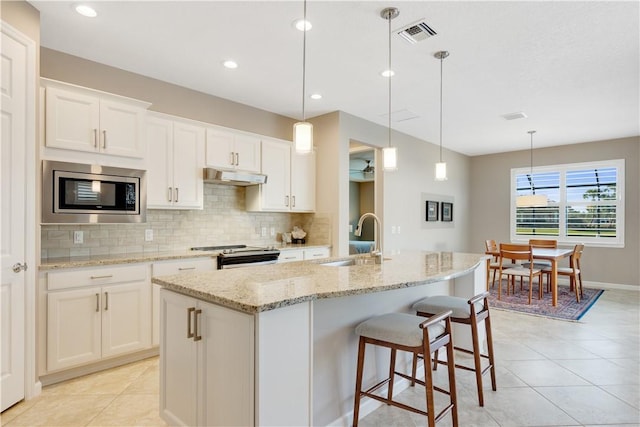 kitchen featuring sink, white cabinetry, hanging light fixtures, stainless steel appliances, and a kitchen island with sink