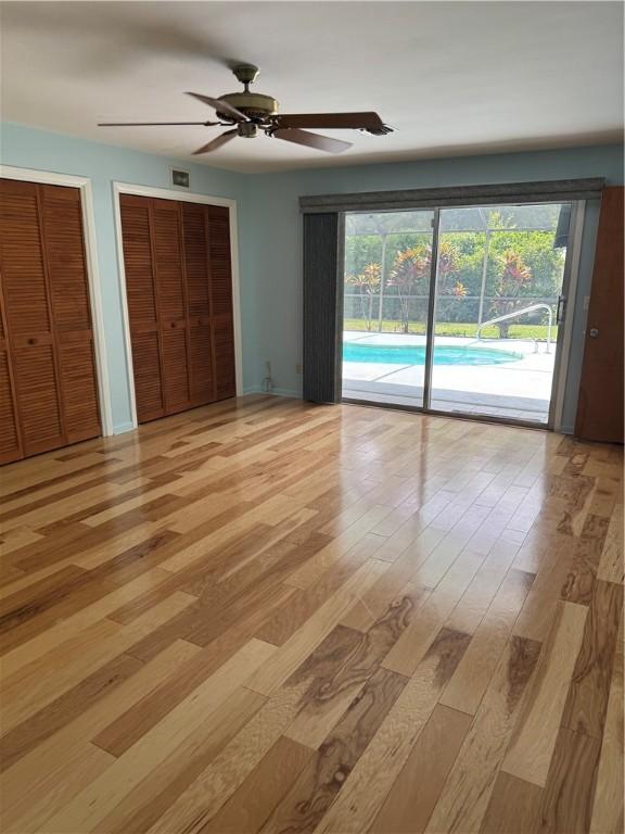 2525 84th Ter, Vero Beach, FL 32966 - unfurnished bedroom featuring access to exterior, light wood finished floors, multiple closets, and a ceiling fan