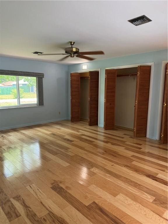 2525 84th Ter, Vero Beach, FL 32966 - unfurnished bedroom featuring two closets, light wood-style flooring, and a ceiling fan